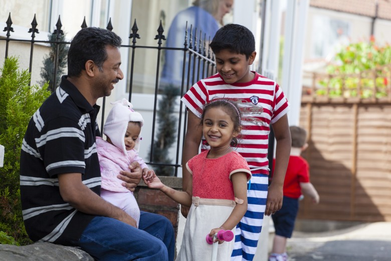 A dad and his children sitting on a wall
