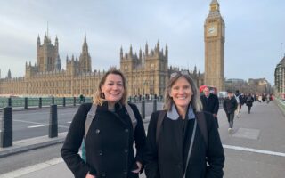 Alice Ferguson and Ingrid Skeels, Playing Out Directors, standing in front of the UK Houses of Parliament